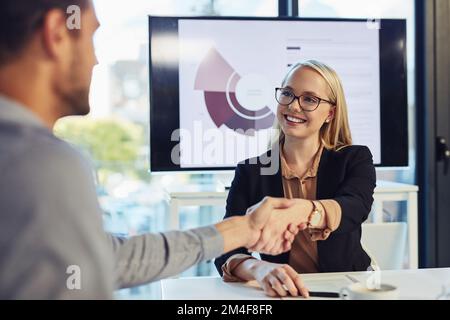 Wir fördern das Geschäft, indem wir das Beste holen. Eine junge Geschäftsfrau und ein Geschäftsmann, die sich während eines Meetings in einem modernen Büro die Hand schütteln. Stockfoto