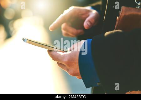 Es fühlt sich an, als ob es ein anstrengender Tag wird. Ein nicht wiedererkennbarer Mann, der auf sein Handy schrieb, während er darauf wartete, dass ein Taxi morgens zur Arbeit kam. Stockfoto