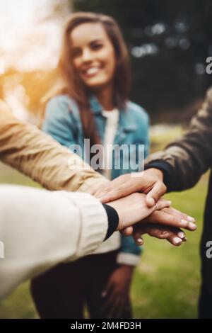 Ich bin froh, mit euch allen in einem Team zu sein. Eine Gruppe von fröhlichen jungen Freunden, die tagsüber draußen mit geteilten Händen zusammenkommen. Stockfoto