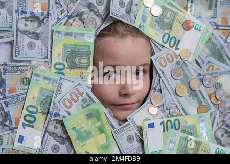 Euro- und Dollar-Konzept. Kinder wie man reich ist. Kind mit Dollarscheinen im Gesicht. Finanzielle Unabhängigkeit und die Fähigkeit, viel Geld zu verdienen. Einkaufen Stockfoto