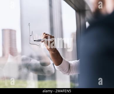 Visualisierung großer Ideen. Nahaufnahme einer unbekannten Geschäftsfrau, die in einem Büro an eine Glaswand schreibt. Stockfoto