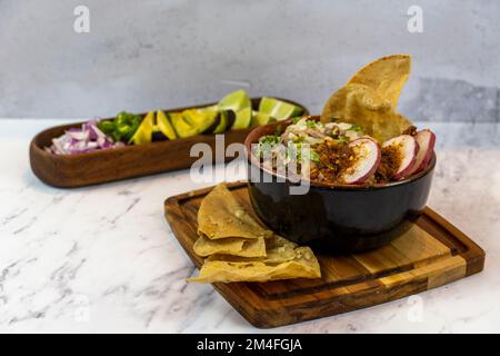 Avocado, Zwiebeln und Koriander zu Fleisch im Saft, typisch mexikanisches Essen mit Stein- und Holzhintergrund, mexiko-lateinamerika Stockfoto