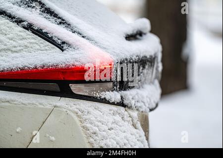 Autos, die auf verschneiten Straßen geparkt wurden, Seitenansicht hinten, selektiver Fokus auf die Heckleuchten Stockfoto