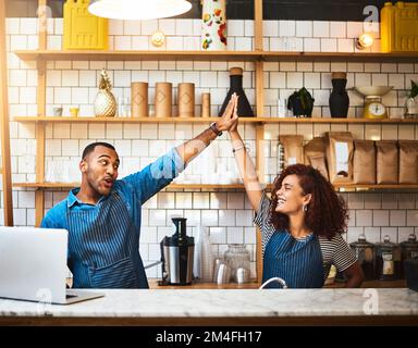 Bumm. Ein liebevolles junges Paar, das High Five in seinem Coffee Shop macht. Stockfoto