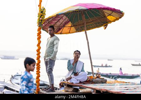 Varanasi, Indien - 2022. November: Touristen führen Rituale zusammen mit Brahminern im Dashwamedh ghat in varanasi am Wintermorgen durch. Stockfoto