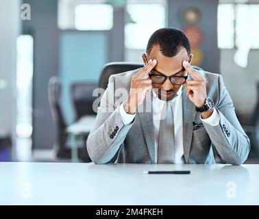 Es kann schwierig sein, es an die Spitze zu schaffen. Ein junger Geschäftsmann, der gestresst im Büro aussieht. Stockfoto