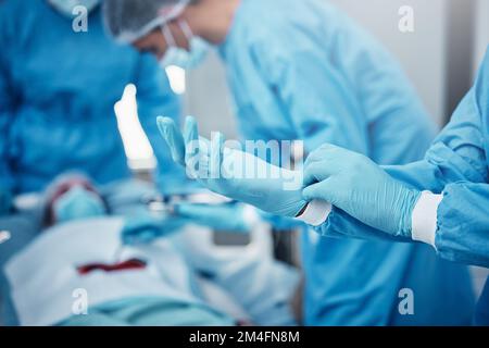 Krankenhaus, Chirurgie und Ärzte im Team mit Handschuhen, ppe und Sicherheit, um Patienten mit Magenkrebs im Bett zu helfen. Doktor Teamarbeitsgruppe, medizinische Operation Stockfoto