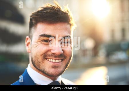 Es war nie langweilig, wenn ich auf der Straße spazieren ging. Porträt eines fröhlichen jungen Geschäftsmanns, der morgens in den belebten Straßen der Stadt steht. Stockfoto
