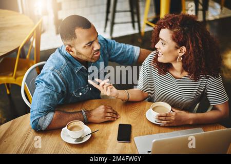 Wir verbringen das Wochenende zusammen. Ein Foto aus dem Blickwinkel eines jungen Paares, das an einem Laptop arbeitet, während es in einem Café sitzt. Stockfoto