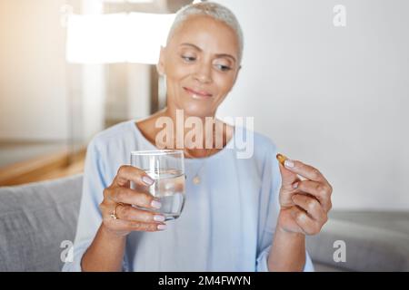 Seniorin, Schwangerschaftspillen und Wasser auf dem Sofa zu Hause für ivf-Gesundheitsbehandlung, Mutter-Wellness und Schwangerenvorsorge. Ältere Frau, trinken Sie Vitamin Stockfoto