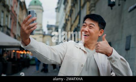 Fröhliche Erwachsene männliche Tourist hält Smartphone Blick auf Bildschirm nehmen Bilder auf Webcam glücklicher Mann Blogger posiert für Foto-Fotografie mit Telefon zu Stockfoto