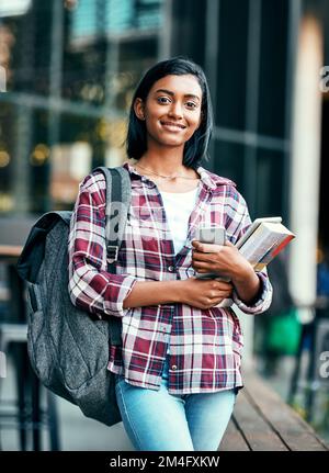 Lehrbücher und schwere Taschen, Zeit fürs College. Porträt einer jungen Studentin draußen auf dem Campus. Stockfoto