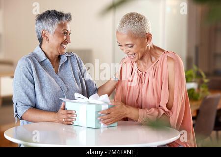 Freunde, Geschenk und glücklich mit Frauen und Box für Weihnachten, Feier und Geburtstagsüberraschung zu Hause. Geschenk, Urlaub und festlich mit Seniorin im Stockfoto