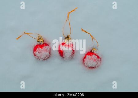 Weihnachtskugeln mit Schnee bedeckt, drei rote Kugeln Stockfoto