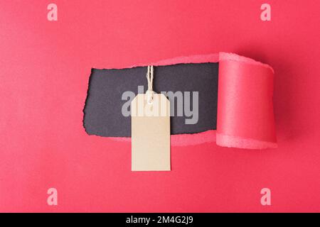 Kraftpapieretikett auf rotem Papierhintergrund. Black friday, Weihnachtsangebot. Draufsicht, flaches Lay, Modell Stockfoto