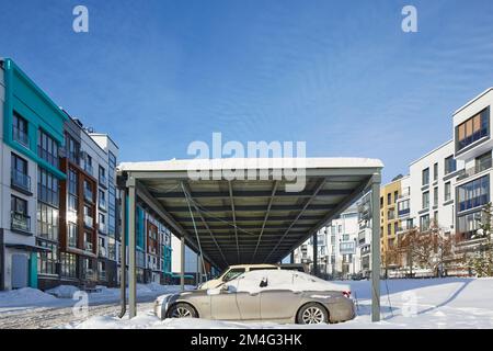 New Metal Carport für öffentliche Parkplätze vor Multi Residential Winter. Gebäude. Parkplätze im Freien unter dem Schneeplatz mit Auto. Stockfoto