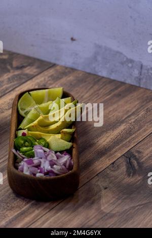 Avocado, Zwiebeln und Koriander zu Fleisch im Saft, typisch mexikanisches Essen mit Stein- und Holzhintergrund, mexiko-lateinamerika Stockfoto