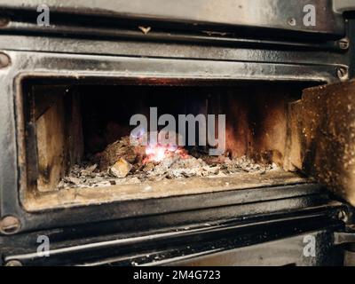 Feuer im Metallherd – Makronahaufnahme in einem bayerischen Kachelofen, Bayern, Deutschland, Europa Stockfoto