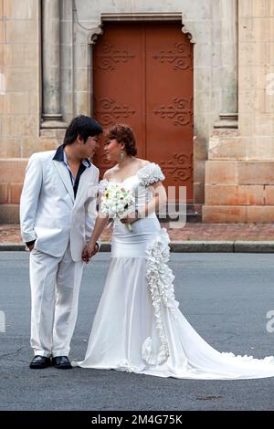 Vietnamesisches Paar mit Blumenstrauß für ein traditionelles Hochzeitsfoto, Kathedrale Notre Dame, Saigon, Vietnam Stockfoto