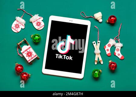 Bangkok, Thailand. Dezember 2022 Smartphone Tik Tok Anwendungssymbol, Logo auf dem Bildschirm, kabellose Kopfhörer auf grünem Hintergrund trendiges Social-Media-Netzwerkkonzept Flat Lay Top Ansicht Neujahr Weihnachten. Stockfoto