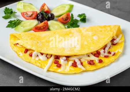 Omelett mit Fetakäse und türkischer Wurst auf einer weißen Porzellanplatte Stockfoto