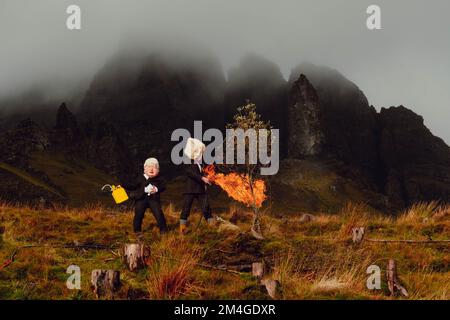 Isle of Skye, Schottland, Vereinigtes Königreich. 24.. Okt. 2021. Eine Person mit einer Boris-Johnson-Maske und eine andere mit einem Öltank als Kopf, die Ölfirmen repräsentiert, benutzt einen Flammenwerfer, um einen Baum zu verbrennen, der den letzten Baum auf Erden darstellt. Dieser theatralische Protest wurde von Ocean Rebellion, einer Schwesterbewegung des Aussterbens Rebellion, im Old man of Storr auf der schottischen Isle of Skye vor dem Start der COP 26 in Glasgow inszeniert. Stockfoto