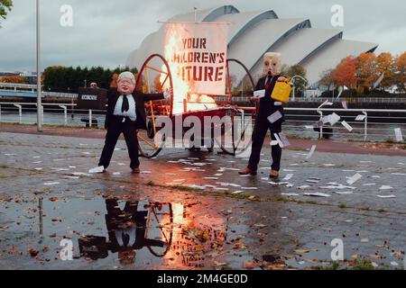 Schottland, Großbritannien. 27.. Oktober 2021. Eine Person, die sich als Boris Johnson ausgab und eine andere mit einem Öltank als Kopf, setzte ein Boot in Brand vor dem UN COP26 Konferenzzentrum in Glasgow. Diese Theateraktion wird von Mitgliedern der Ocean Rebellion inszeniert, einer Schwestergruppe zur Ausrottung der Rebellion. Stockfoto