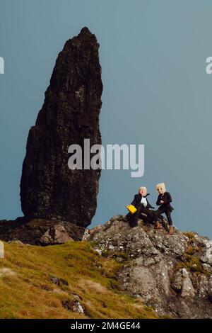 Isle of Skye, Schottland, Vereinigtes Königreich. 24.. Okt. 2021. Eine Person mit einer Boris-Johnson-Maske und eine andere mit einem Öltank als Kopf, die Ölfirmen repräsentiert, benutzt einen Flammenwerfer, um einen Baum zu verbrennen, der den letzten Baum auf Erden darstellt. Dieser theatralische Protest wurde von Ocean Rebellion, einer Schwesterbewegung des Aussterbens Rebellion, im Old man of Storr auf der schottischen Isle of Skye vor dem Start der COP 26 in Glasgow inszeniert. Stockfoto