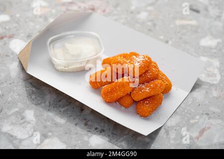 Essenslieferung, Käsestifte zum Mitnehmen, Papierbehälter mit panierten Mozzarella-Käsestiften und Sauce. Menü, Nahaufnahme Stockfoto