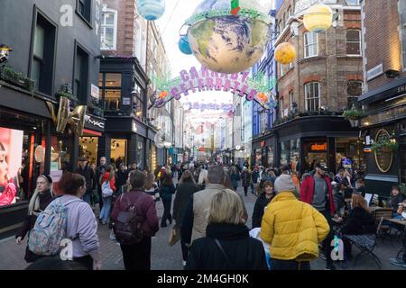 London, UK, 20. Dezember 2022: Die Carnaby Street in Soho bietet Shopping-Fans vor Weihnachten ein mildes und trockenes Wetter. Über der Fußgängerzone hängen aufwendige Dekorationen, aber an einigen Tagen wurden die Fußgänger durch Zugstreiks verringert. Anna Watson/Alamy Live News Stockfoto