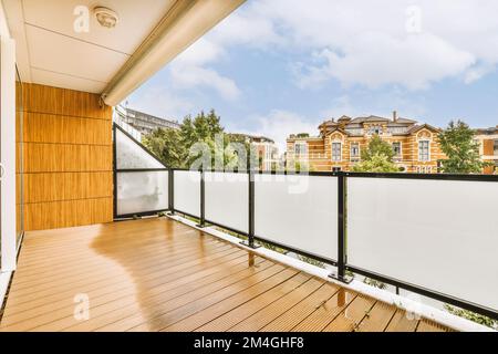 Ein Balkon mit Holzfußboden und weißen Geländern an der Seite des Hauses mit Blick auf die Straße Stockfoto