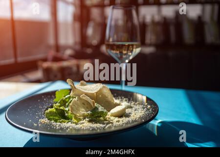 Wein und caesar Salat mit Hühnerfleisch und Salat auf schwarzem Teller im Restaurant Stockfoto