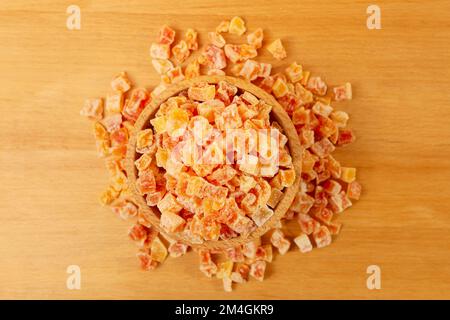 Gewürfelte kandierte Papaya in Holzschüssel auf Holzbrett. Stockfoto