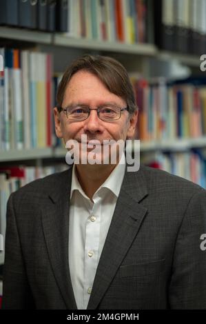 Trier, Deutschland. 21.. Dezember 2022. Uwe Jun, ein Politikwissenschaftler aus Trier, steht vor einem Bücherregal in seinem Büro an der Universität Trier. Außerdem ist er Direktor eines neuen Instituts für Demokratie und Parteiforschung an der Universität Trier. Kredit: Harald Tittel/dpa/Alamy Live News Stockfoto