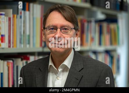 Trier, Deutschland. 21.. Dezember 2022. Uwe Jun, ein Politikwissenschaftler aus Trier, steht vor einem Bücherregal in seinem Büro an der Universität Trier. Außerdem ist er Direktor eines neuen Instituts für Demokratie und Parteiforschung an der Universität Trier. Kredit: Harald Tittel/dpa/Alamy Live News Stockfoto