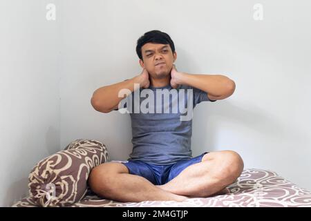 Porträt asiatischer Indonesier Mann streckt seine Hände in einem Schlafzimmer nach dem Aufwachen aus dem Schlafhaus gesundes Konzept isolierter weißer Hintergrund Stockfoto