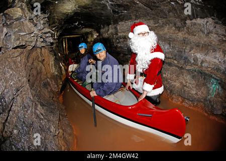 21. Dezember 2022, Sachsen-Anhalt, Wettelrode: Besucher aus Seesen lassen sich vom Weihnachtsmann auf eine Führung durch das Bergwerk Röhrigschacht im Seegen Gottes adit mitnehmen. Mit dieser Aktion überraschte das Team der Besuchermine seine Gäste. Seit etwa 20 Jahren bietet das Erlebniszentrum Bergbau Röhrigschacht Wettelrode längere Untergrundausflüge in einer Tiefe von ca. 300 Metern an. Seit einigen Jahren gibt es eine Tour, bei der ein Teil der Strecke von Paddelbooten befahren wird. Die ersten Bergleute begannen vor etwa 800 Jahren, in der Region Mansfeld nach Kupfererz zu graben. Seit dem Jahr 1750 war carrie Bergbau Stockfoto
