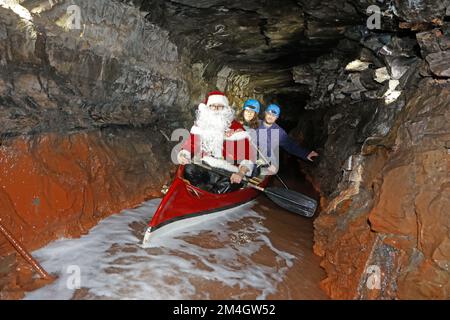21. Dezember 2022, Sachsen-Anhalt, Wettelrode: Besucher aus Seesen lassen sich vom Weihnachtsmann auf eine Führung durch das Bergwerk Röhrigschacht im Seegen Gottes adit mitnehmen. Mit dieser Aktion überraschte das Team der Besuchermine seine Gäste. Seit etwa 20 Jahren bietet das Erlebniszentrum Bergbau Röhrigschacht Wettelrode längere Untergrundausflüge in einer Tiefe von ca. 300 Metern an. Seit einigen Jahren gibt es eine Tour, bei der ein Teil der Strecke von Paddelbooten befahren wird. Die ersten Bergleute begannen vor etwa 800 Jahren, in der Region Mansfeld nach Kupfererz zu graben. Seit dem Jahr 1750 war carrie Bergbau Stockfoto