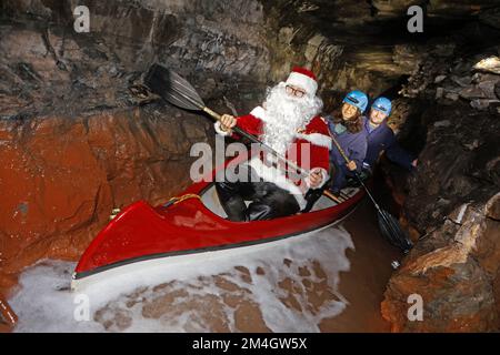 21. Dezember 2022, Sachsen-Anhalt, Wettelrode: Besucher aus Seesen lassen sich vom Weihnachtsmann auf eine Führung durch das Bergwerk Röhrigschacht im Seegen Gottes adit mitnehmen. Mit dieser Aktion überraschte das Team der Besuchermine seine Gäste. Seit etwa 20 Jahren bietet das Erlebniszentrum Bergbau Röhrigschacht Wettelrode längere Untergrundausflüge in einer Tiefe von ca. 300 Metern an. Seit einigen Jahren gibt es eine Tour, bei der ein Teil der Strecke von Paddelbooten befahren wird. Die ersten Bergleute begannen vor etwa 800 Jahren, in der Region Mansfeld nach Kupfererz zu graben. Seit dem Jahr 1750 war carrie Bergbau Stockfoto