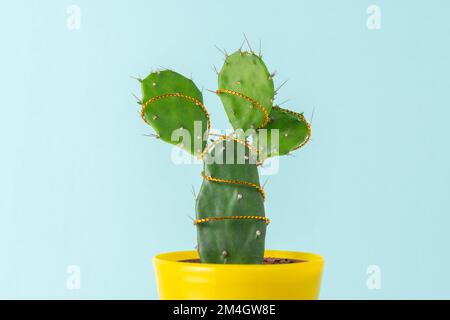Minimalistisches Konzept mit grünem Kaktus und Weihnachtsbaumschmuck. Hintergrund für Weihnachten oder Neujahr. Stockfoto