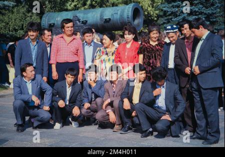 Historisches Bild einer Gruppe von Männern, russische Touristen gemischter ethnischer Gruppen posieren für ein Foto vor der Zarenkanone, Kreml, Moskau, 1990 Stockfoto