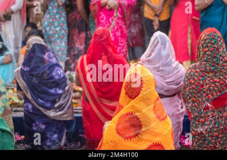 Frauen, die im Fluss stehen und für den sonnengott im Chhath-Festival beten Stockfoto