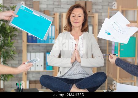 Ruhige junge Geschäftsfrau, die Yoga-Übungen am Arbeitsplatz macht Stockfoto