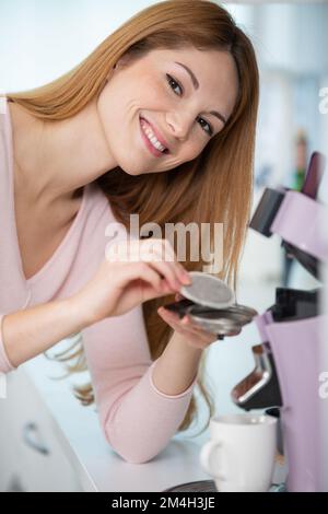 Frau, die eine Kaffeekapselmaschine in der Küche benutzt Stockfoto