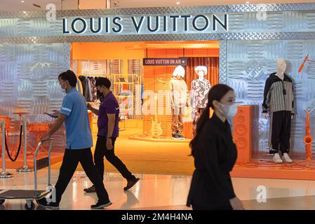 Die Leute gehen vorbei an einem Louis Vuitton Store im Siam Paragon Einkaufszentrum in Bangkok. Stockfoto