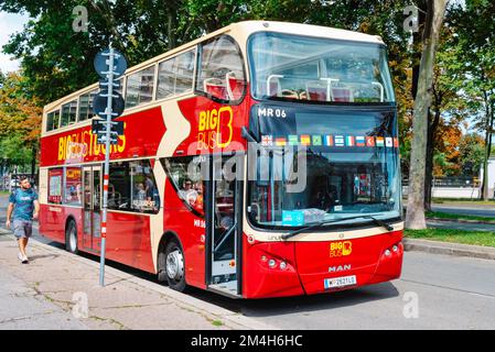 Wien, Österreich - 28. August 2022: Ein Doppeldeckerbus hält an der Straße neben einem Wahrzeichen in Wien, Österreich