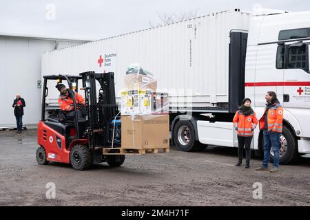 Dresden, Deutschland. 21.. Dezember 2022. Mitarbeiter des Deutschen Roten Kreuzes Sachsen verwenden einen Gabelstapler, um Medikamente und Notstromgeneratoren für die Ukraine zu laden. Die Hilfslieferungen gehen an acht ukrainische Städte, von denen sieben bereits eine Zwillingsstadt in Sachsen haben. Kredit: Sebastian Kahnert/dpa/Alamy Live News Stockfoto