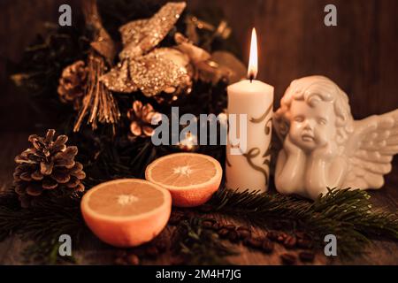 Weihnachtsengel-Komposition, Kerze und Kaffeebohnen auf einem dunklen Tisch Stockfoto