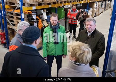 Dresden, Deutschland. 21.. Dezember 2022. Michael Kretschmer (CDU, M), Ministerpräsident Sachsens, und Bert Wendsche (r), Präsident des sächsischen Verbandes der Städte und Gemeinden, stehen anlässlich der Verladung von Medikamenten und Notstromgeneratoren für die Ukraine in einem Lagerhaus des Deutschen Roten Kreuzes Sachsen. Die Hilfslieferung geht an acht ukrainische Städte, von denen sieben bereits eine Zwillingsstadt in Sachsen haben. Kredit: Sebastian Kahnert/dpa/Alamy Live News Stockfoto