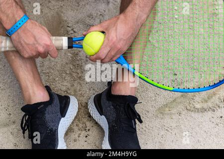 Tennisschläger und Tennisball in den Händen des Menschen. Stockfoto
